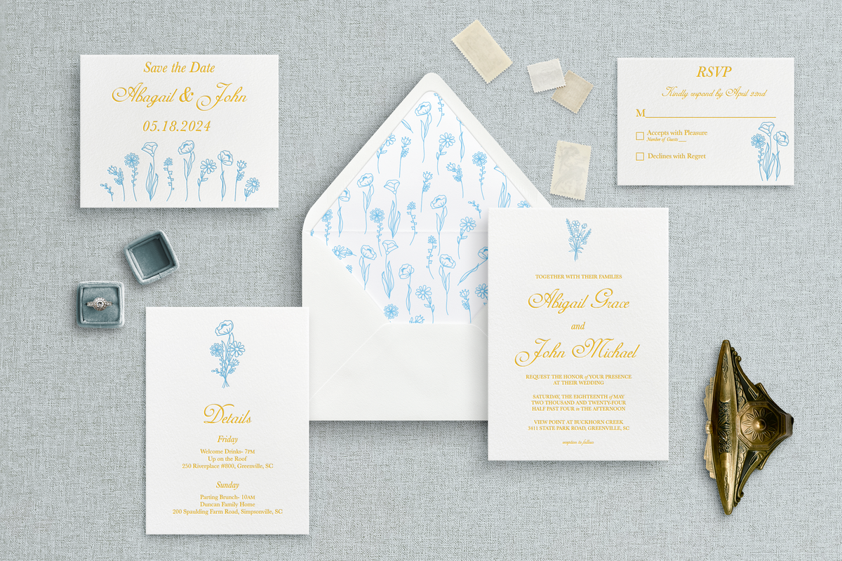 Custom letterpress wedding inviations with yellow text and blue wild flowers. 