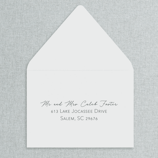 White envelope with black text of your wedding guests' addresses on a gray textured background. 