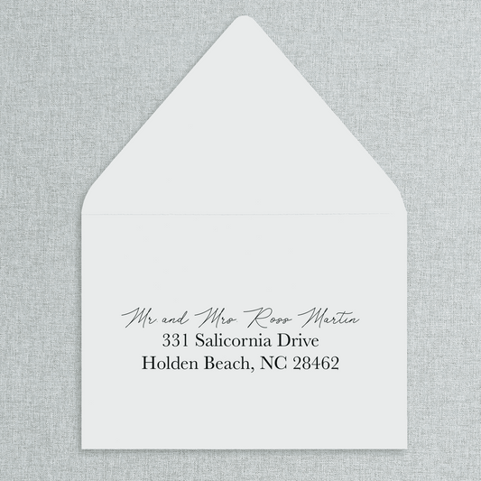 White envelope with black text of your wedding guests' addresses on a gray textured background. 