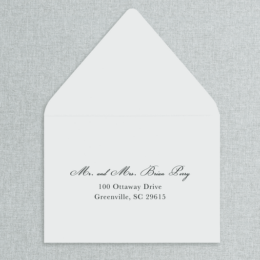 White envelope with black text of your wedding guests' addresses on a gray textured background. 