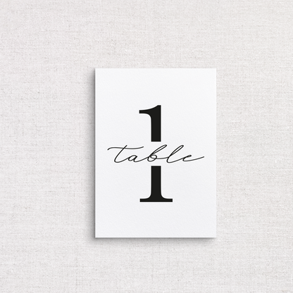 A minimalist white wedding table number print featuring the number 1 with the word 'table' in black cursive script, displayed against a light gray linen-textured background.
