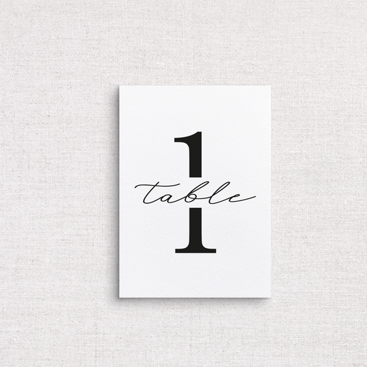 A minimalist white wedding table number print featuring the number 1 with the word 'table' in black cursive script, displayed against a light gray linen-textured background.