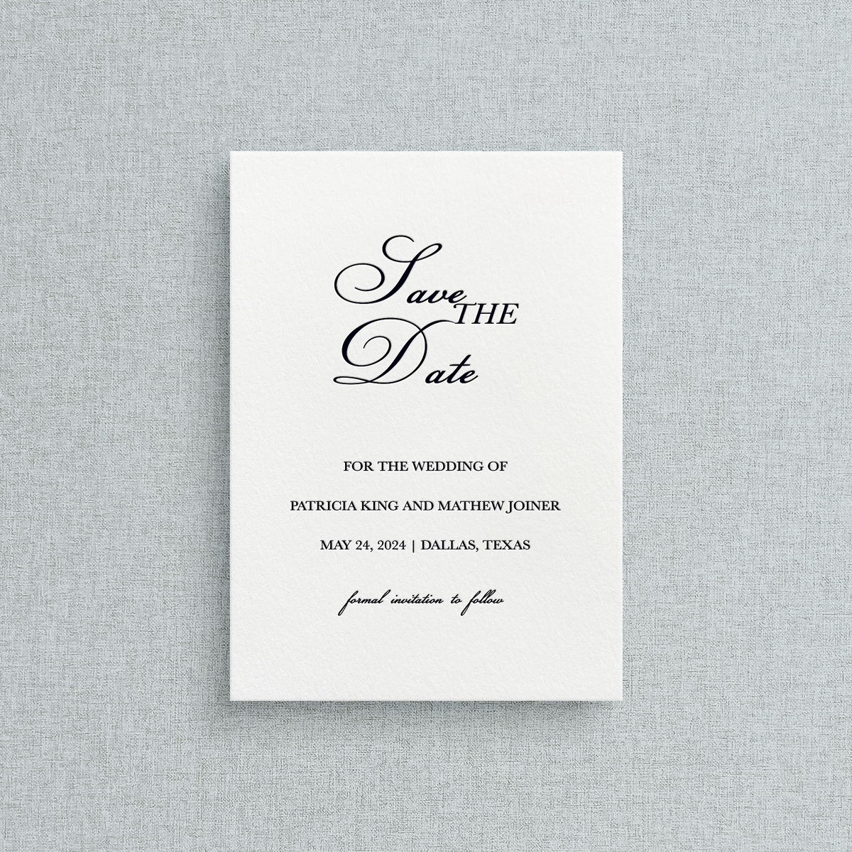 Semi-custom letterpress Save the Date card with black text on a white background, placed on a gray textured surface.