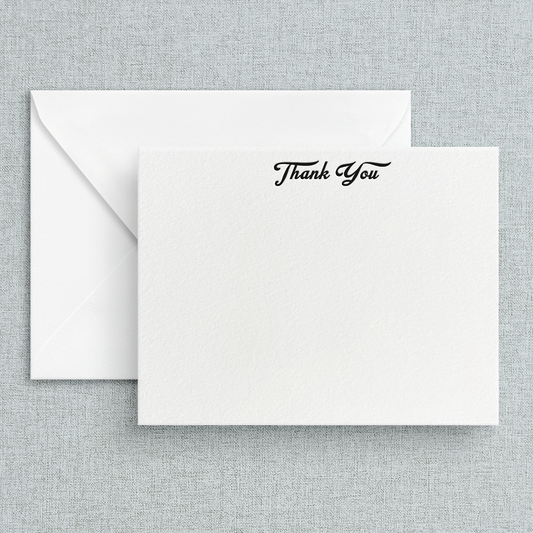 A simple letterpress print 'Thank You' note on a white background with black cursive text, accompanied by a white envelope.