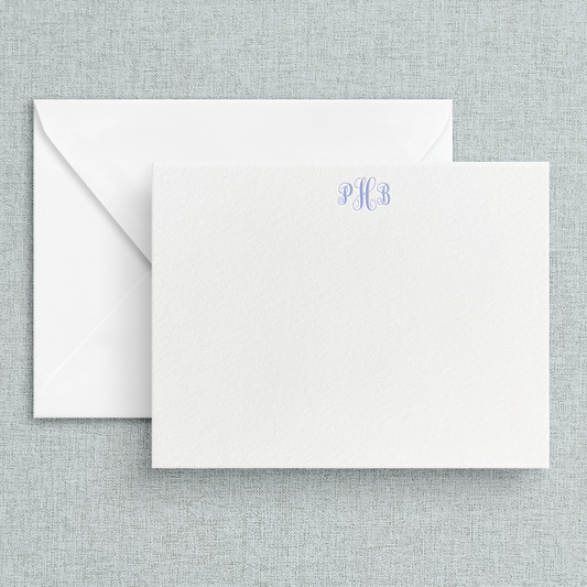A set of custom letterpress stationery cards with a circle script monogram at the top, displayed with white envelopes.